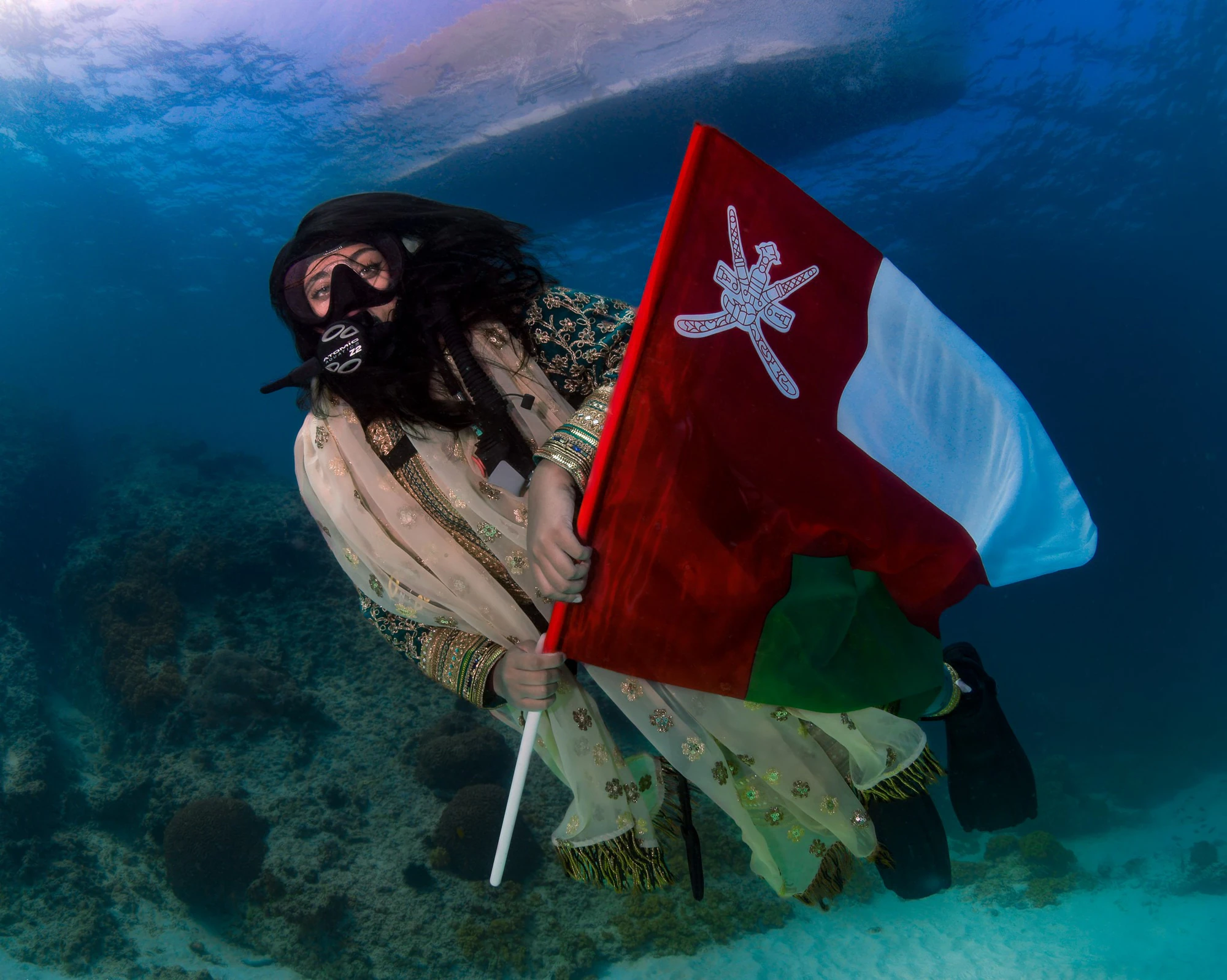 Diver holding the Omani flag underwater