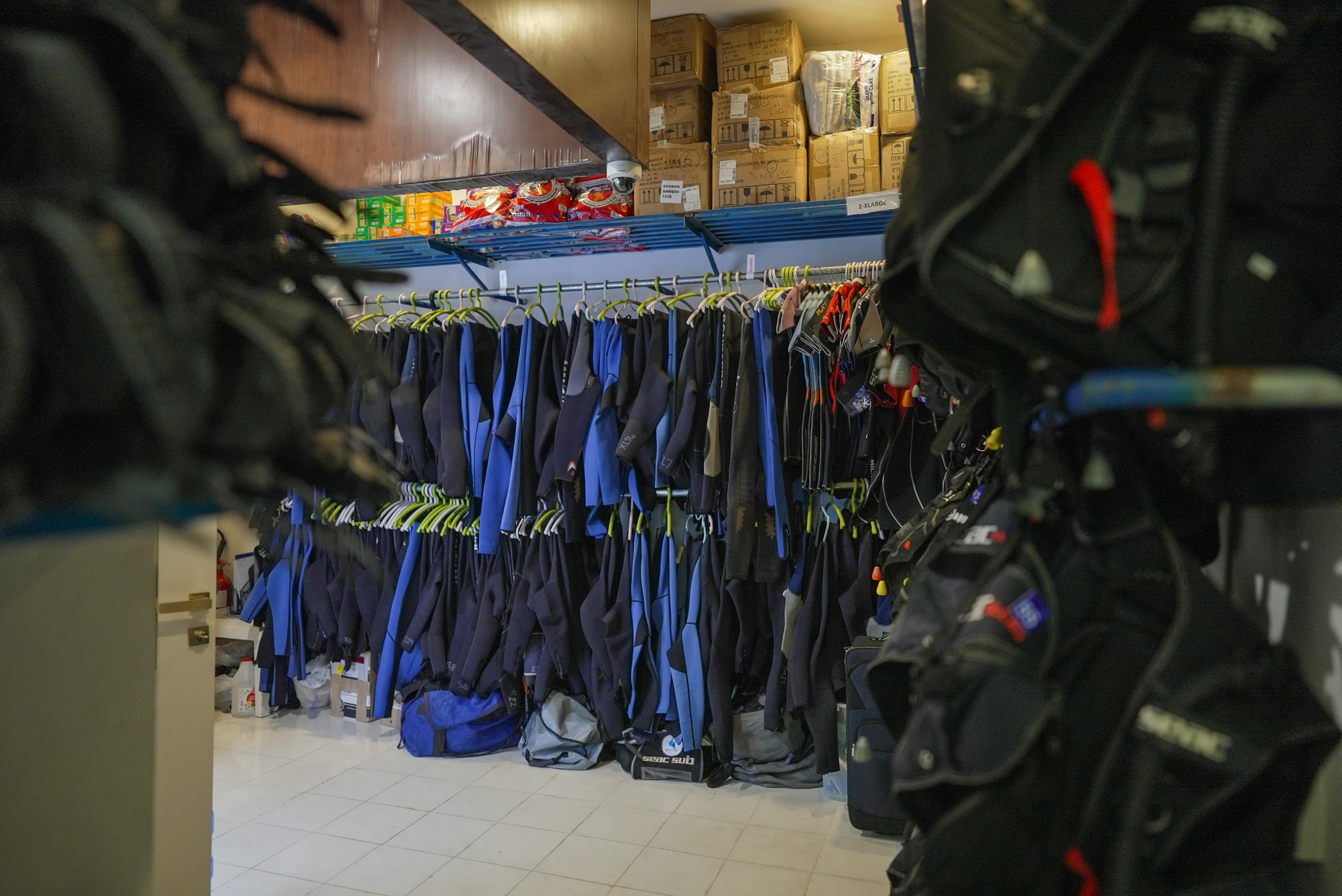 Gear room with wetsuits and BCDs