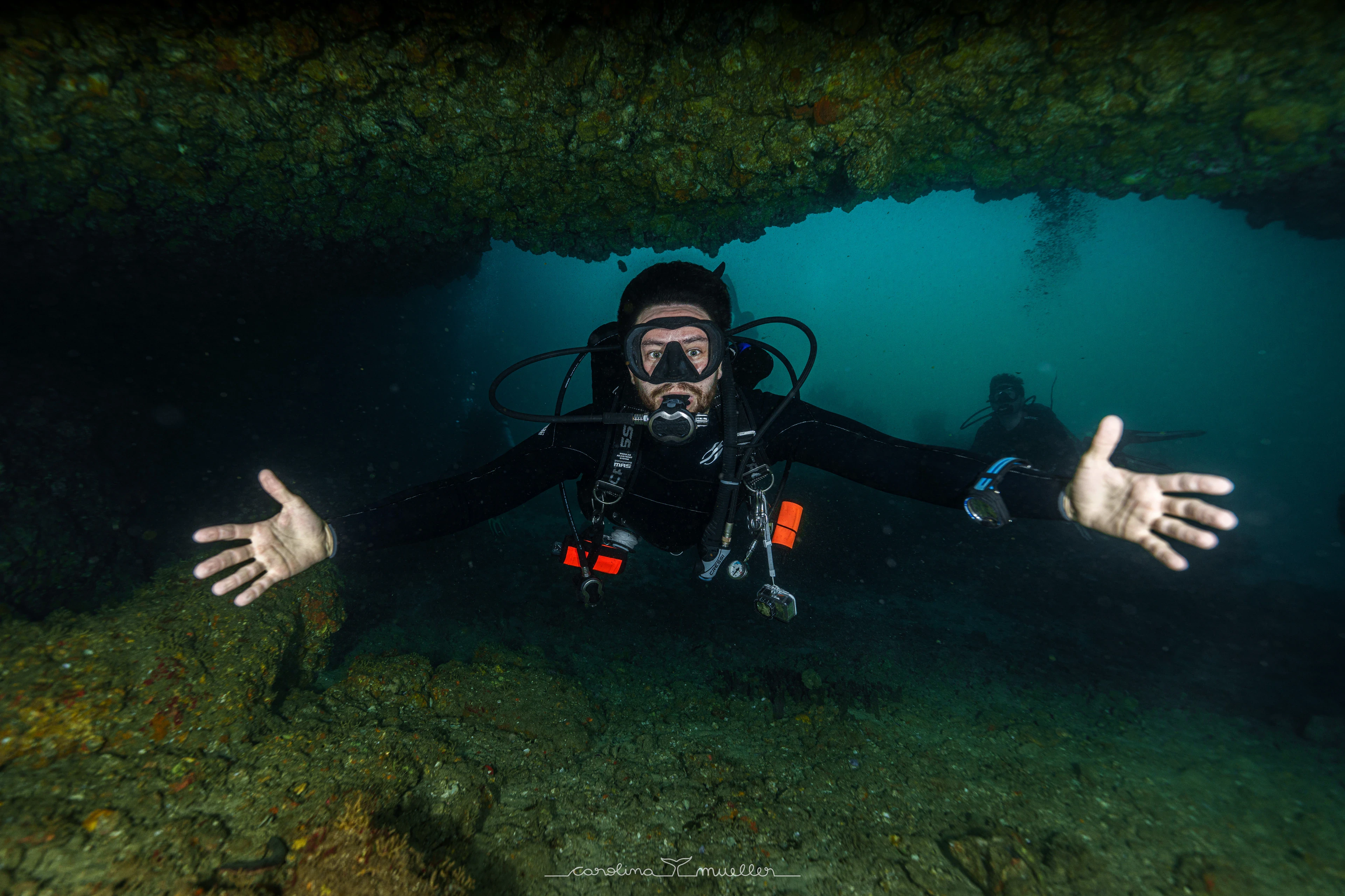 Diver spreading their arms inside an underwater cave