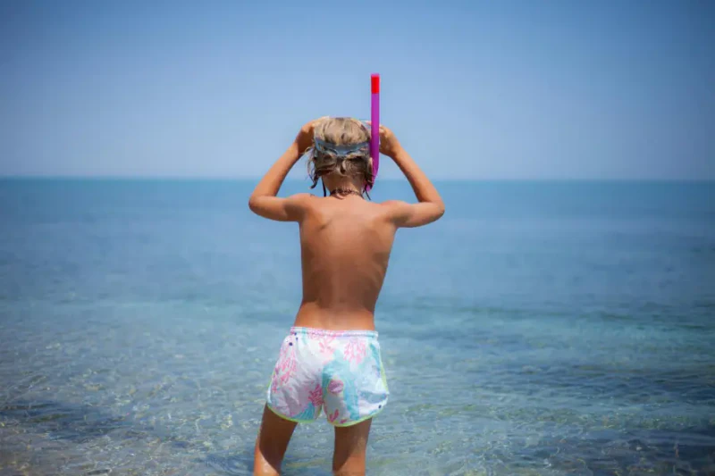 Child putting on a snorkel mask at the beach